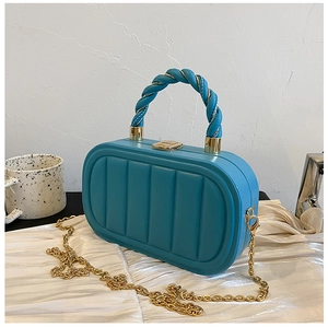Detail of blue quilted hardshell bag with golden twist handle and chain strap
