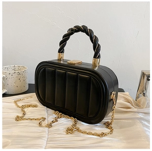 Detail of black oval hard-shell handbag with vertical quilting and gold chain strap