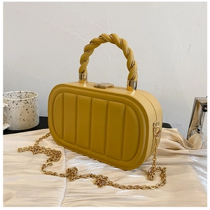 Close-up of mustard yellow quilted handbag with gold chain strap on white silk fabric