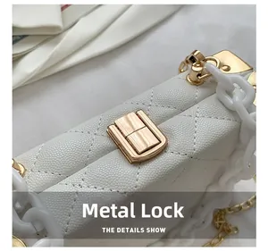 Macro shot of white lychee leather texture with gold metal clasp and acrylic chain