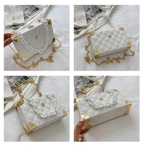 Detail view of white quilted box bag with rose ornament and acrylic chain strap