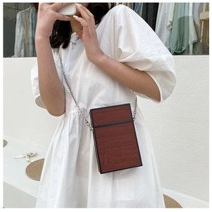 Brown wood grain box bag with silver chain strap shown on a white summer dress