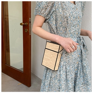 Detail view of mini wood grain crossbody bag with silver chain worn on floral dress