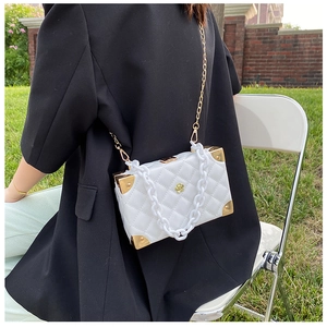 Detail of white quilted box bag featuring acrylic chain and gold corner hardware