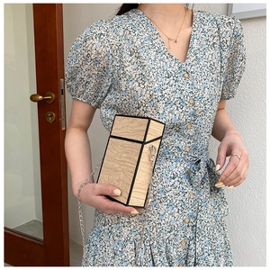 Close-up of a structured wood grain box bag with silver chain and floral print dress