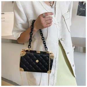 Close-up of black lychee-patterned box bag with gold flower buckle and acrylic chain