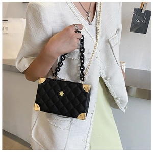 Detail of lychee textured box bag with gold flower logo and acrylic chain link