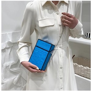 Blue wood grain box bag with silver chain strap shown on a model's shoulder