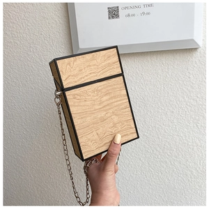 Detail of wood grain textured box bag with black edges and silver chain strap