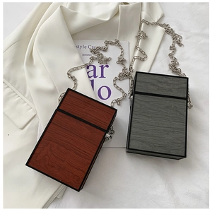Detailed top view of wood grain box bags with silver chains on a white suit