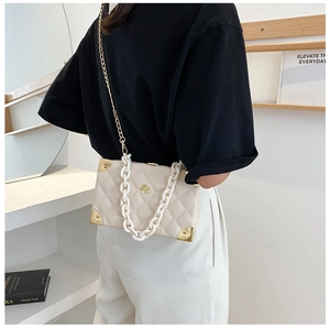 Detail of lychee pattern crossbody bag featuring acrylic chain and gold metal corners