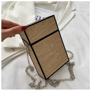Detail of structural wooden texture box bag with silver chunky chain and black trim edges