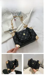 Detail of black lychee texture box bag with gold floral clasp and acrylic chain strap