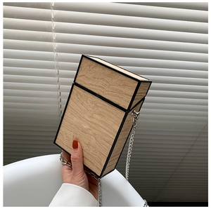 Detailed view of rectangular wood grain box bag with black edges and silver chain strap