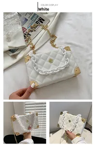 Detail of white lychee textured box bag with floral clasp and acrylic chain strap