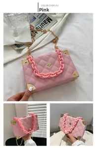 Detailed view of pink quilted box bag with gold metal corners and resin chain strap