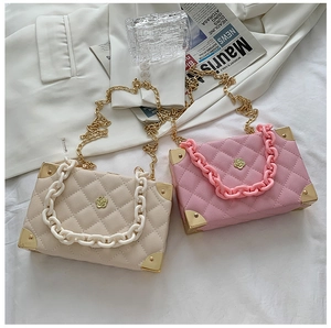 Close-up of quilted square bags with acrylic chains and gold corner accents