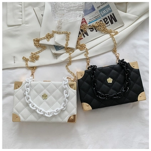 Close-up of box bags with quilted texture and gold acrylic chain on blazer backdrop