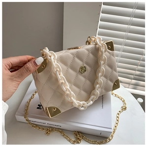 Detail of beige quilted leather bag with gold floral clasp and acrylic chain strap