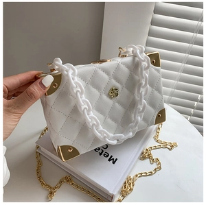 Close-up of white quilted box bag with gold flower logo and acrylic chain handle