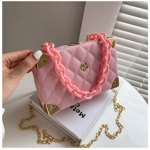 Detail of pink lychee leather bag with gold corners, camellia clasp, and resin chain