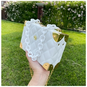 Detailed close-up of white lychee textured crossbody bag with gold corners and acrylic chain