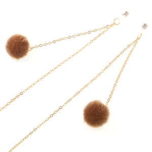 Golden metal glasses chain featuring soft brown fur pompom charms on a white background