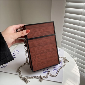 Retro reddish-brown wood grain box bag with silver metal chain strap held in hand