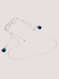 Detail of gold metal eyewear chain with three-tier gradient blue tassels on clear background