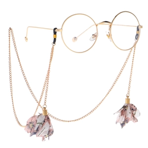 Vintage round gold metal glasses with floral fabric tassel chain on white background