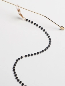 Detail view of black beaded eyewear chain with gold lobster clasp and clear rubber loops