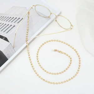 Fashionable gold eyewear chain with sparkling rhinestones on a minimalist magazine backdrop