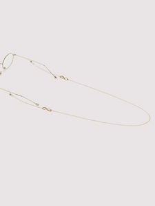 Detail of a thin gold eyewear chain featuring an infinity symbol on a minimalist frame