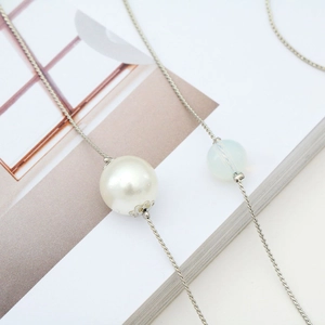 Minimalist silver chain eyewear strap with opal and large white pearl on a magazine
