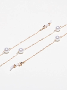 Macro view of golden eyewear chain with elegant white pearls and lobster clasps