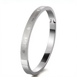 Detailed macro view of stainless steel bracelet with engraved Love Kiss text and matte finish