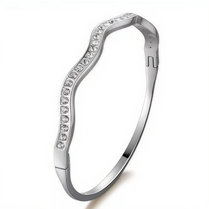 Macro view of crystal paved wavy stainless steel bangle with a secure snap closure