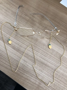 Detail of golden non-slip eyewear chain featuring yellow enamel pineapple pendants
