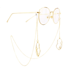 Golden metal eyewear chain with abstract face charms on stylish gold frame glasses