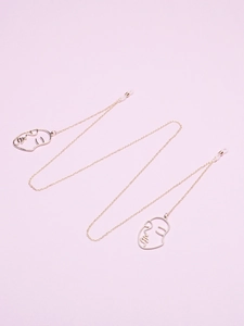 Close-up of gold glasses chain featuring abstract face pendants and non-slip silicone loops