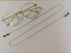 Dettaglio della catenella per occhiali dorata antiscivolo in metallo con anelli di gomma neri