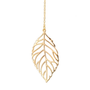 Pendentif feuille dorée ajourée avec chaîne fine sur un fond blanc épuré et brillant