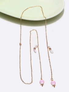 Detail of golden metal eyewear chain featuring pink candy pendant with sparkling rhinestones