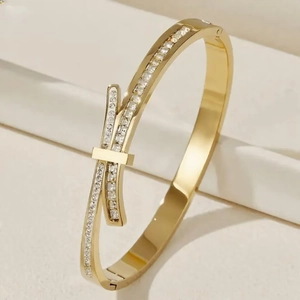 Detail of gold-plated stainless steel cuff with pavé-set zircon ribbon design