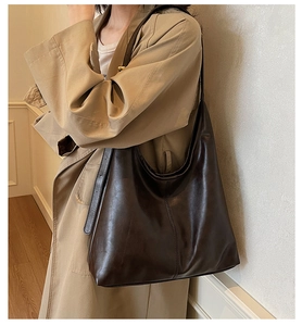 Detail of dark brown leather tote bag showing soft matte texture and stitching accents