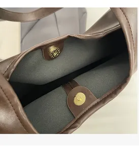 Detail view of premium gold magnetic clasps on a large brown leather tote bag