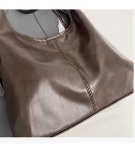 Close-up of soft dark brown hobo bag showing oily wax leather texture and vertical stitching