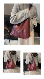 Detail view of burgundy leather tote bag with vertical stitching on model in studio setting