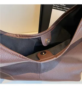 Detail of brown litchi pattern leather tote with magnetic buckle and black fabric lining
