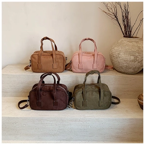 Four textured matte handbags in earthy tones displayed on elegant stone stairs